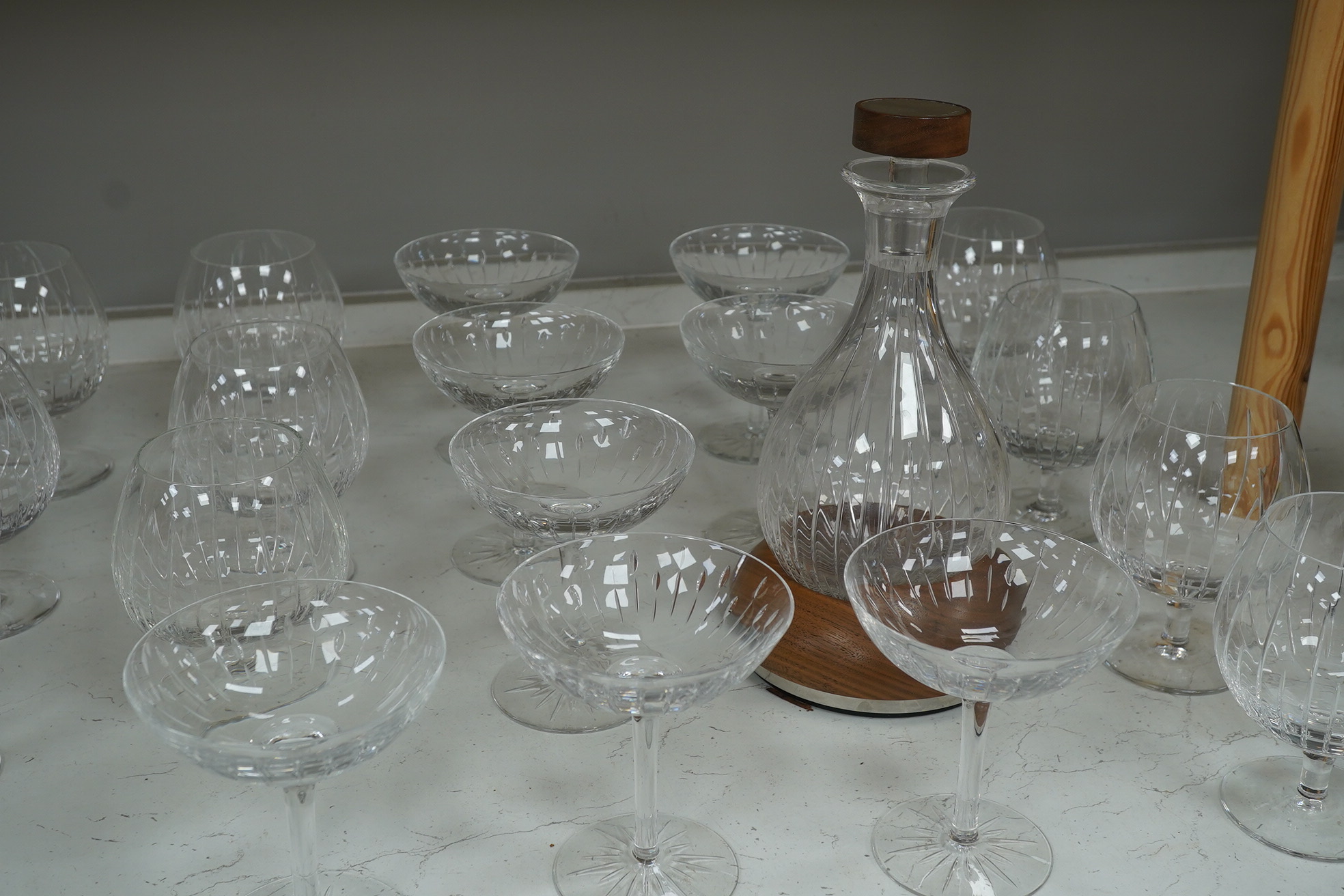 A Linley Glyndebourne pattern cut glass decanter with a silver mounted stopper, on a weighted wooden coaster stand, and a matching set of ten goblets and eight champagne coupes, largest 30cm high. Condition - all in very